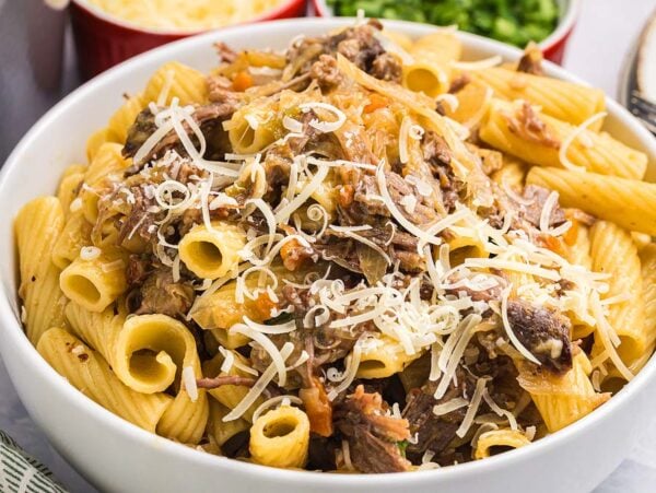 A bowl of rigatoni pasta alla Genovese, topped with tender shredded meat and grated cheese.