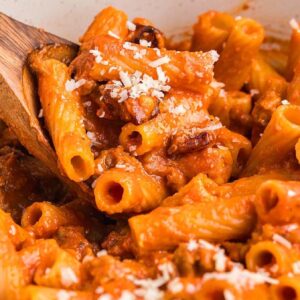 Rigatoni pasta alla zozzona in a rich tomato sauce, topped with grated cheese and stirred gently with a wooden spoon.