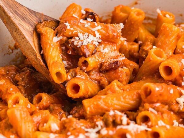 Rigatoni pasta alla zozzona in a rich tomato sauce, topped with grated cheese and stirred gently with a wooden spoon.