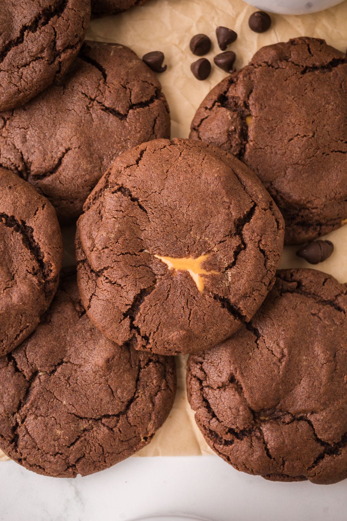 A close-up of several Peanut Butter Stuffed Chocolate Cookies, with one cookie revealing a small melted caramel center.