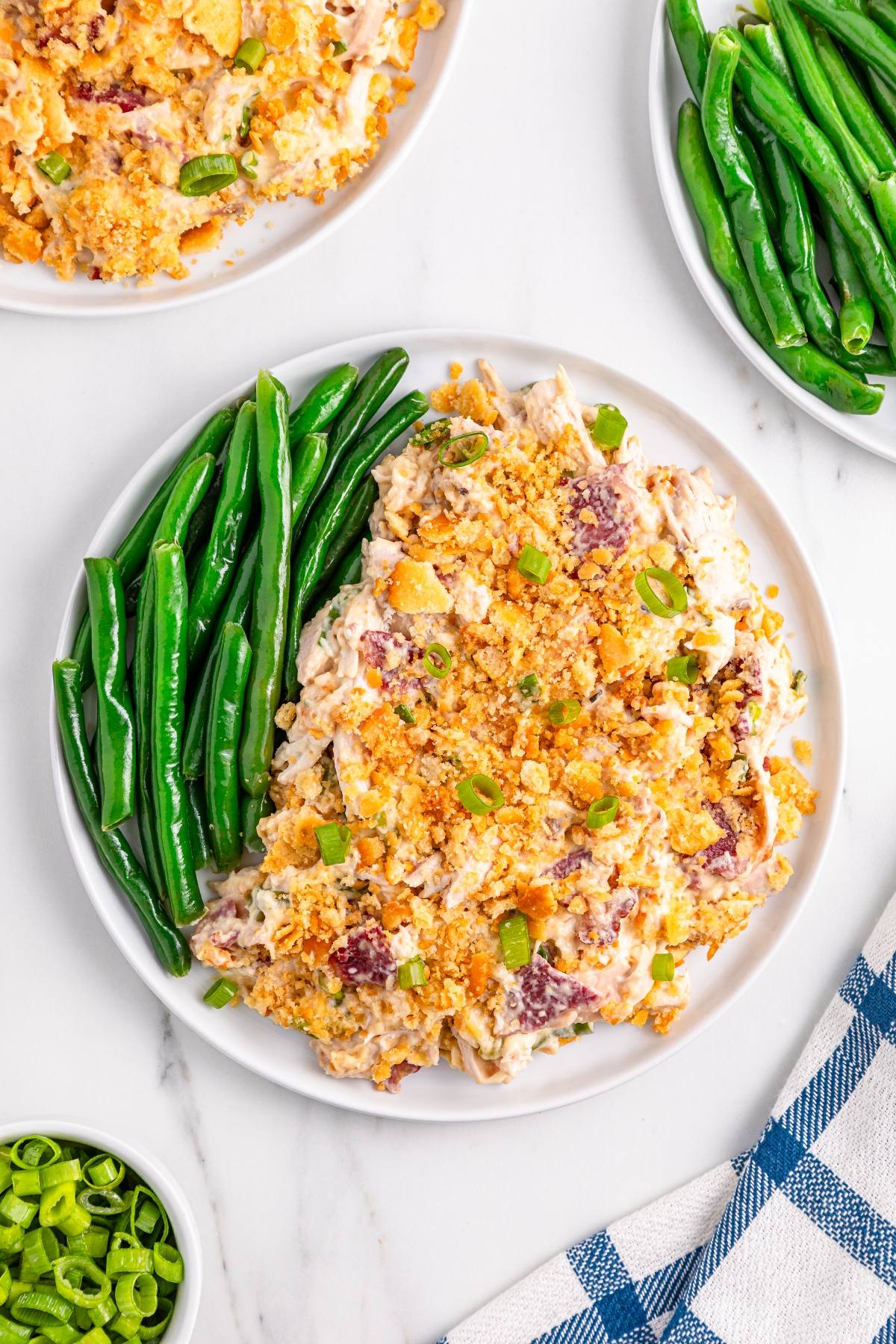 A plate with green beans and a creamy casserole topped with crushed crackers and green onions.