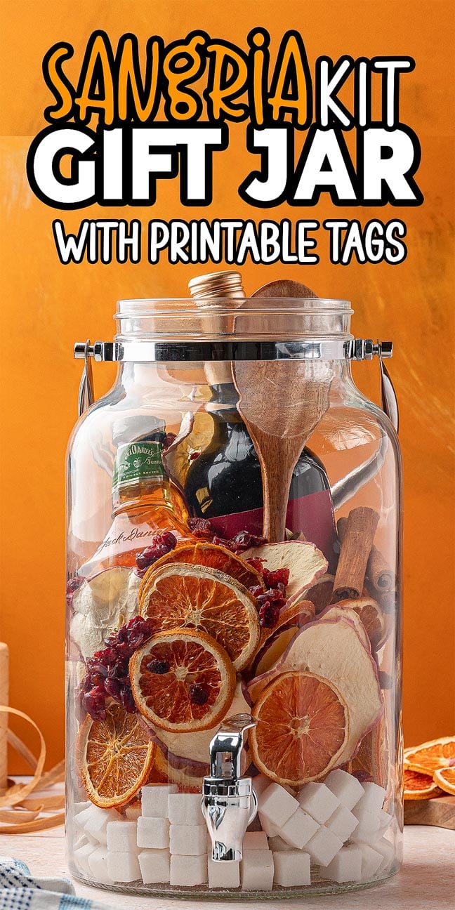 Large glass Sangria Kit Gift Jar filled with dried citrus, spices, sugar cubes, utensils, and a small bottle of liquor.