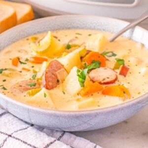 A bowl of creamy Slow Cooker Kielbasa Potato Soup with bread, parsley, and butter on the side.