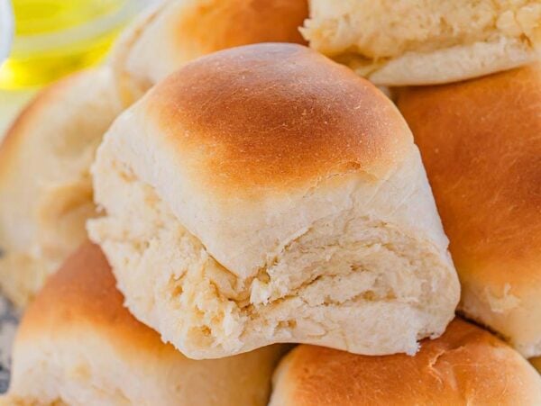 A close-up of a plate piled with golden brown, fluffy 30 Minute Dinner Rolls.