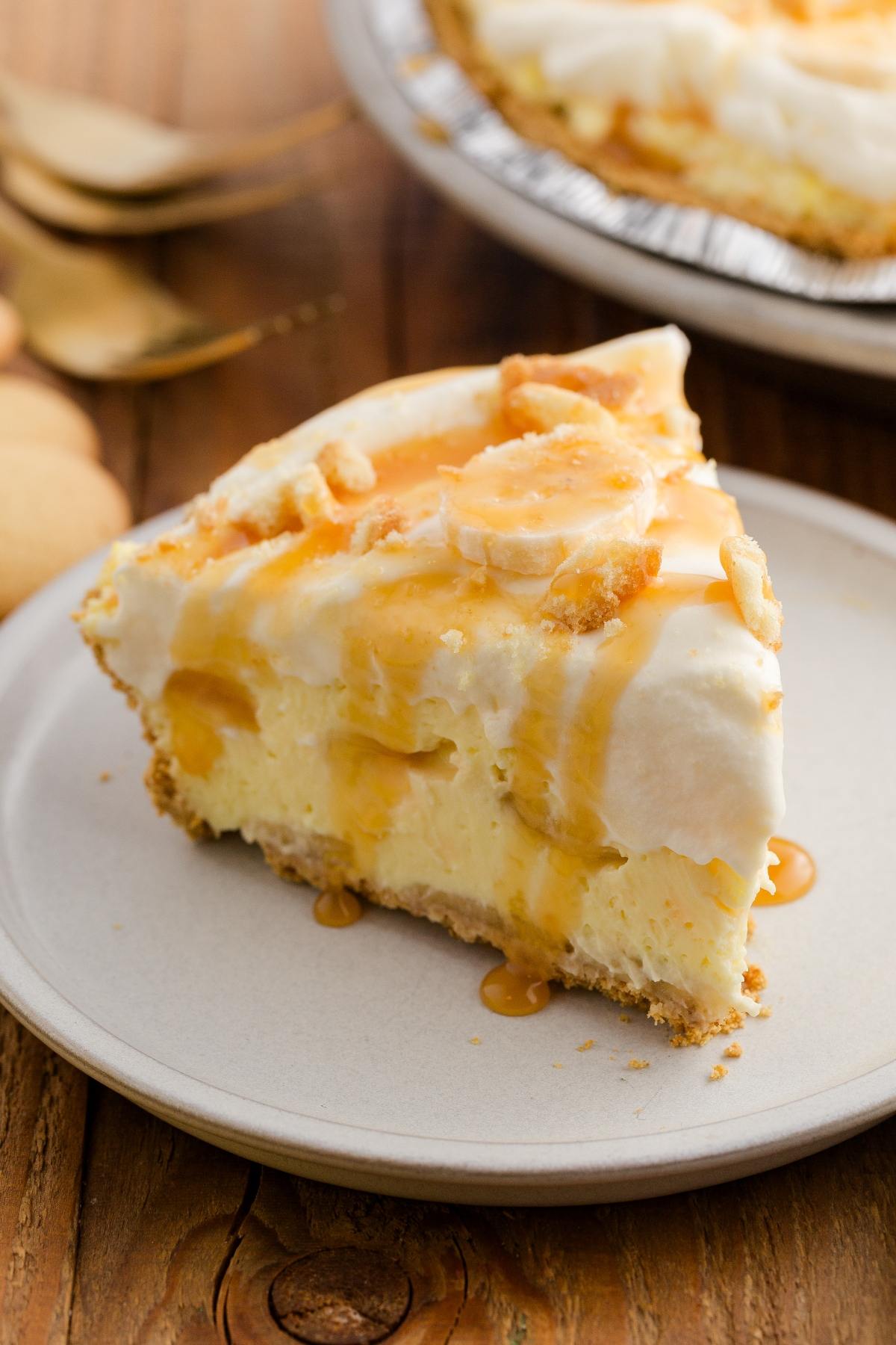 A slice of creamy banana pudding pie with whipped topping and caramel drizzle on a plate.