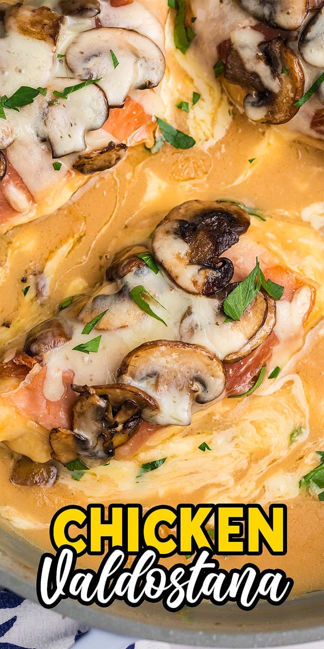 Chicken Valdostana topped with mushrooms and melted cheese in a creamy sauce, garnished with fresh parsley for a classic Italian touch.
