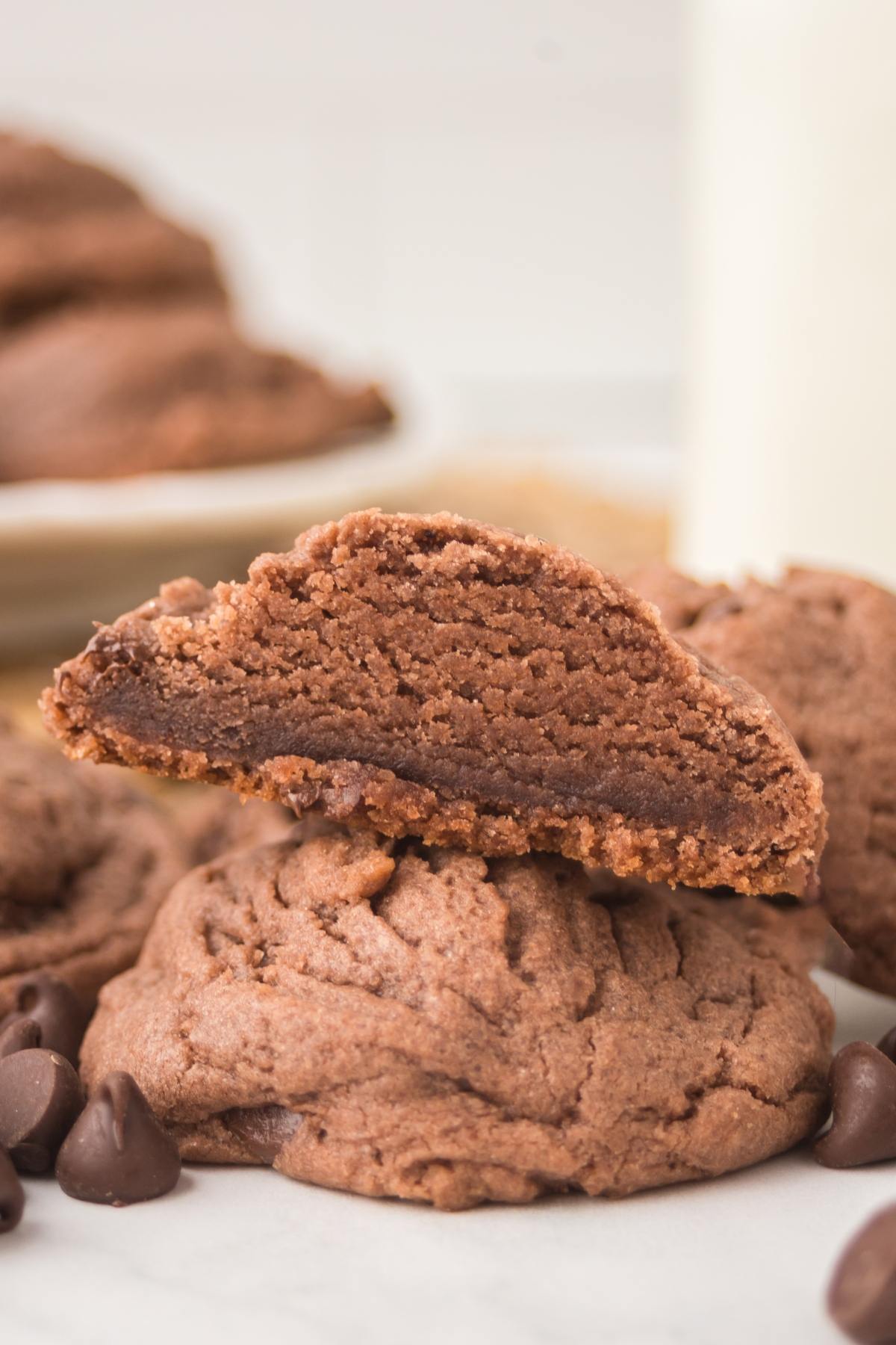 A close-up of thick, soft chocolate cookies, one broken in half to show the fudgy inside.