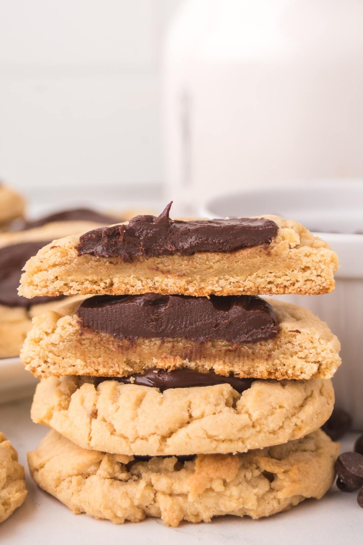 A stack of thick cookies with a chocolate filling, one broken in half to reveal the creamy center.