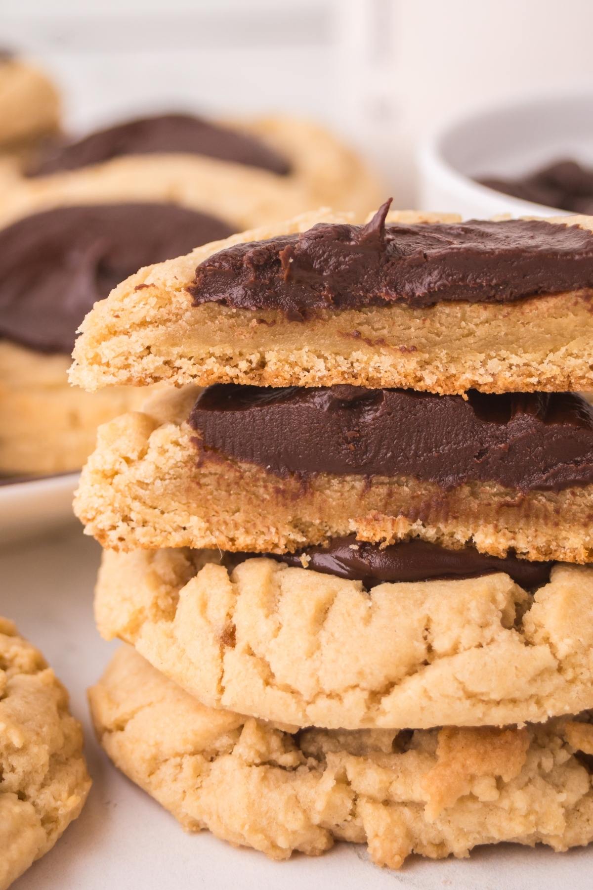 A stack of thick chocolate thumbprint cookies with chocolate frosting on top.