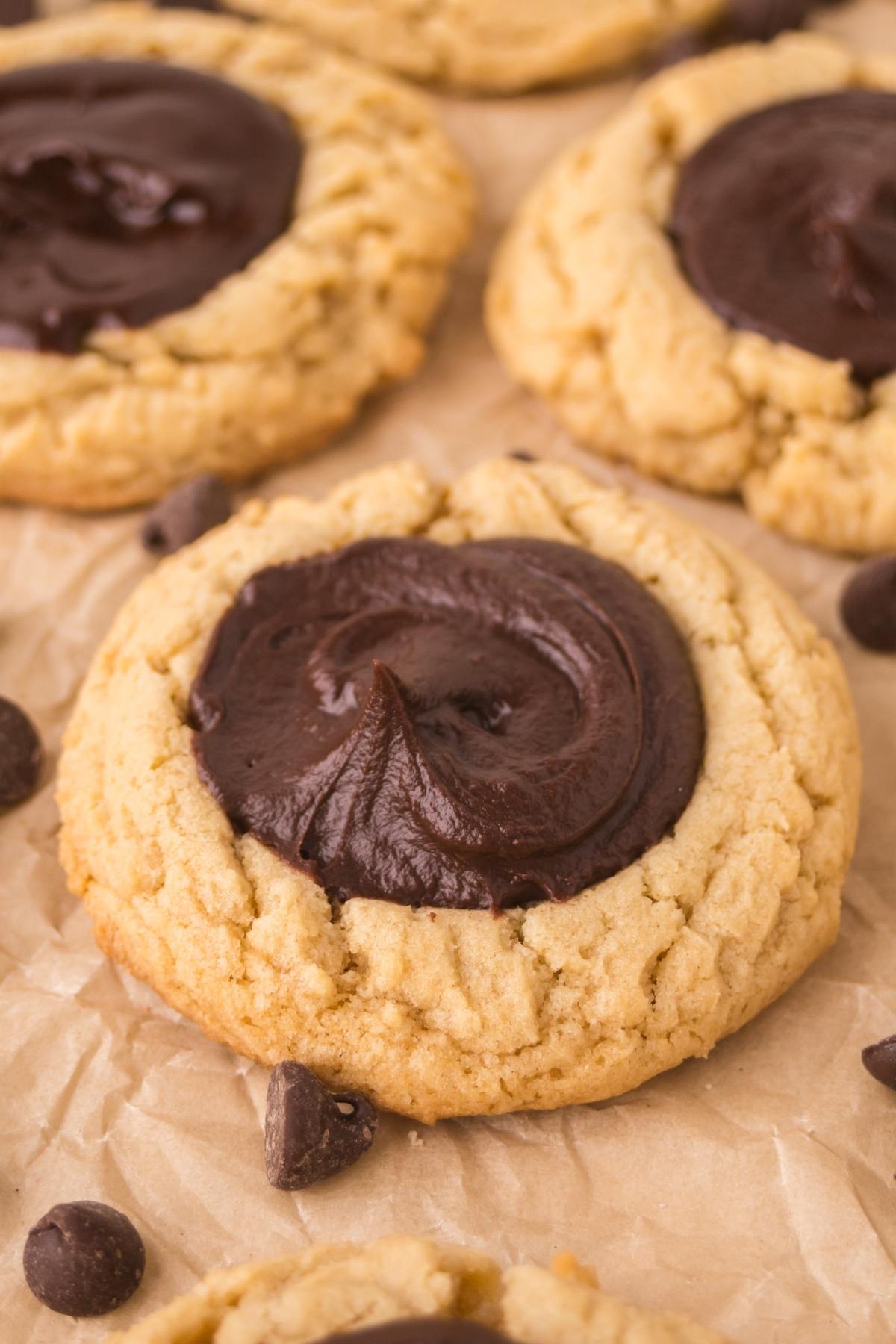 Close-up of chocolate thumbprint cookies on parchment paper with chocolate chips.