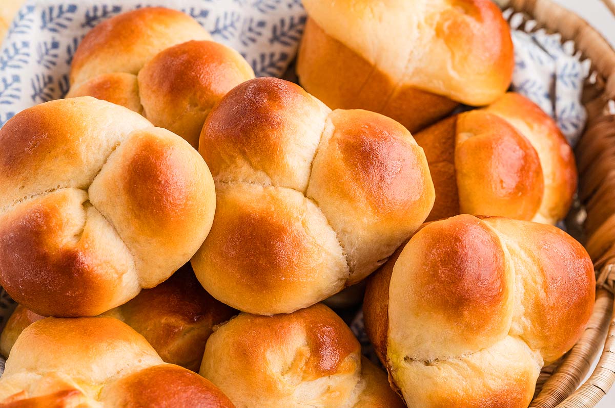 A basket filled with golden brown, freshly baked cloverleaf rolls, their soft layers inviting you to enjoy every bite.