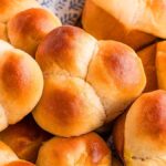 A basket filled with golden brown, freshly baked cloverleaf rolls, their pillowy tops inviting you to enjoy every bite.