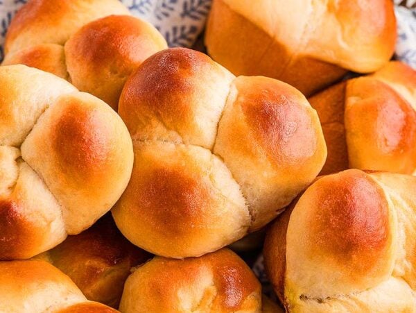 A basket filled with golden brown, freshly baked cloverleaf rolls, their pillowy tops inviting you to enjoy every bite.