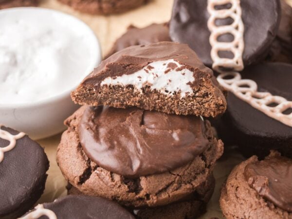 Chocolate sandwich cookies with cream filling, some topped with icing loops.