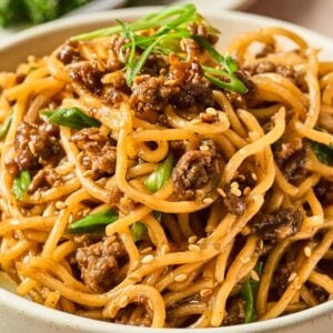 A bowl of Mongolian Ground Beef Noodles mixed with ground meat, green onions, and sesame seeds.