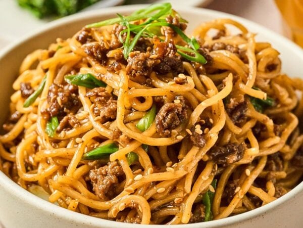 A bowl of Mongolian Ground Beef Noodles mixed with ground meat, green onions, and sesame seeds.