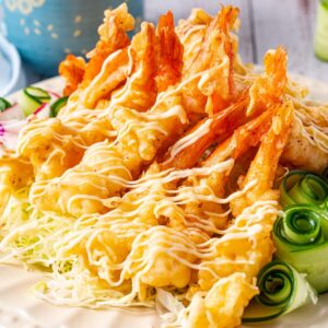 A plate of shrimp tempura is served with a blue cup and a blue mug.