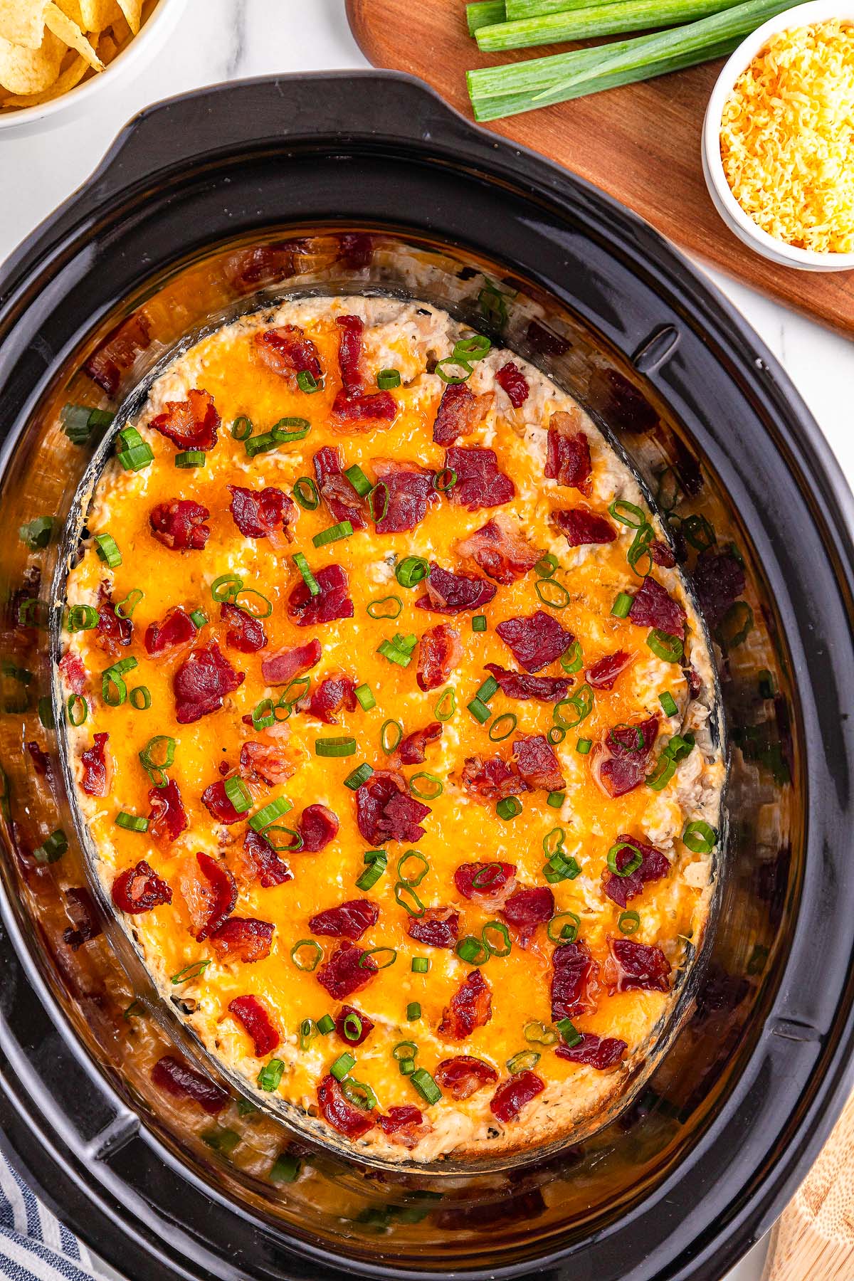 Slow Cooker Crack Chicken topped with bacon and chopped green onions, hot and cheesy right from the slow cooker, ready to serve.