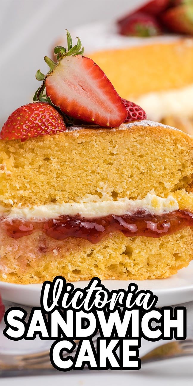 Slice of Victoria Sandwich Cake with strawberries, jam, and cream, finished with a sliced strawberry on top.