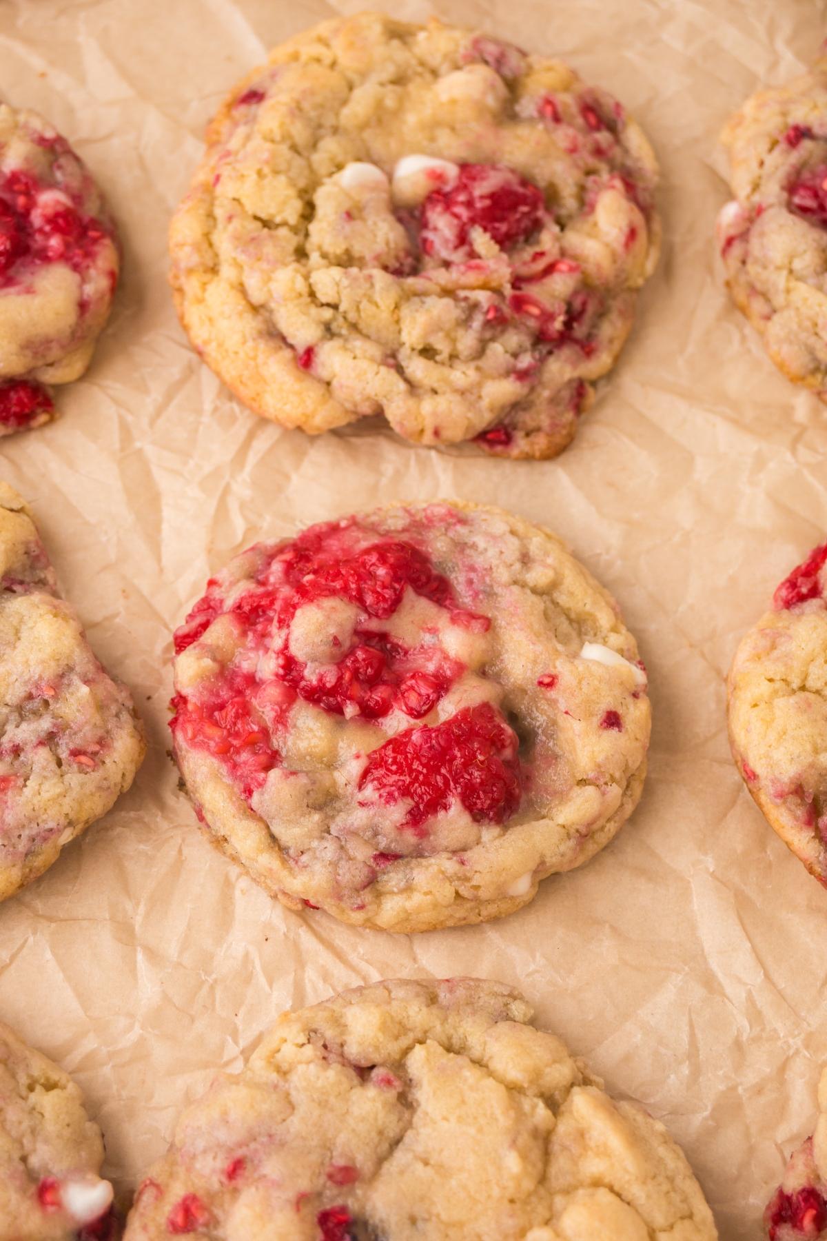 Close-up of raspberry white chocolate cookies on crinkled parchment paper.