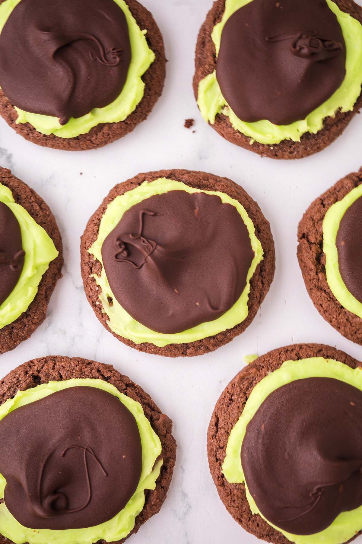 Chocolate mint cookies topped with bright green frosting and a layer of smooth, dark chocolate coating.