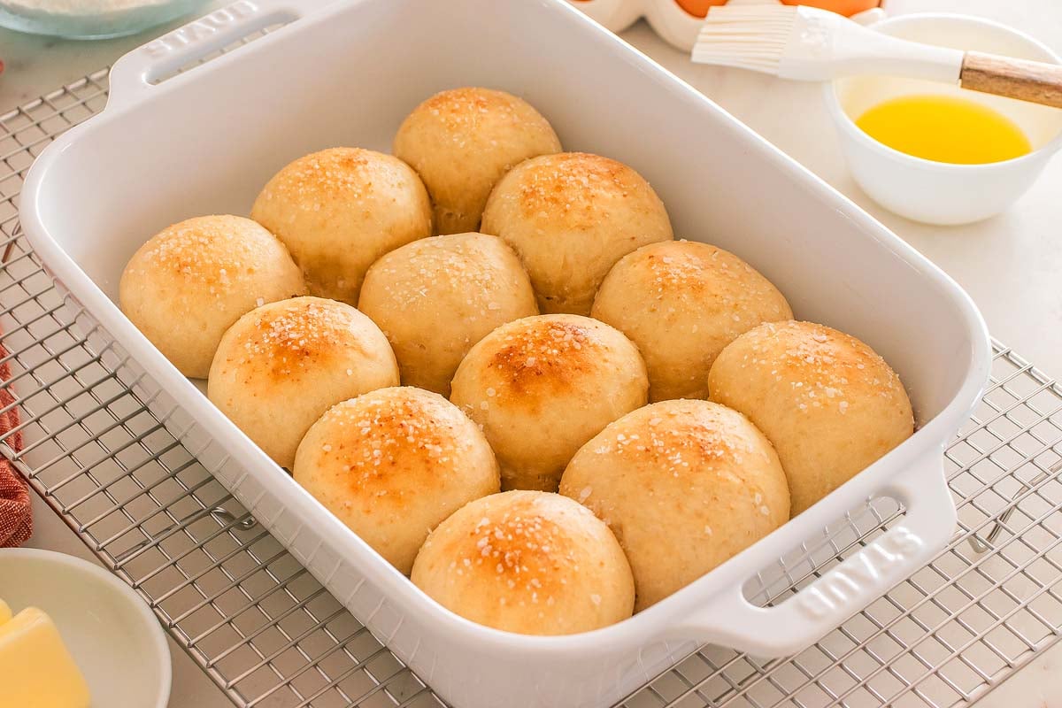 A baking dish filled with golden, round homemade yeast rolls topped with a sprinkle of salt.