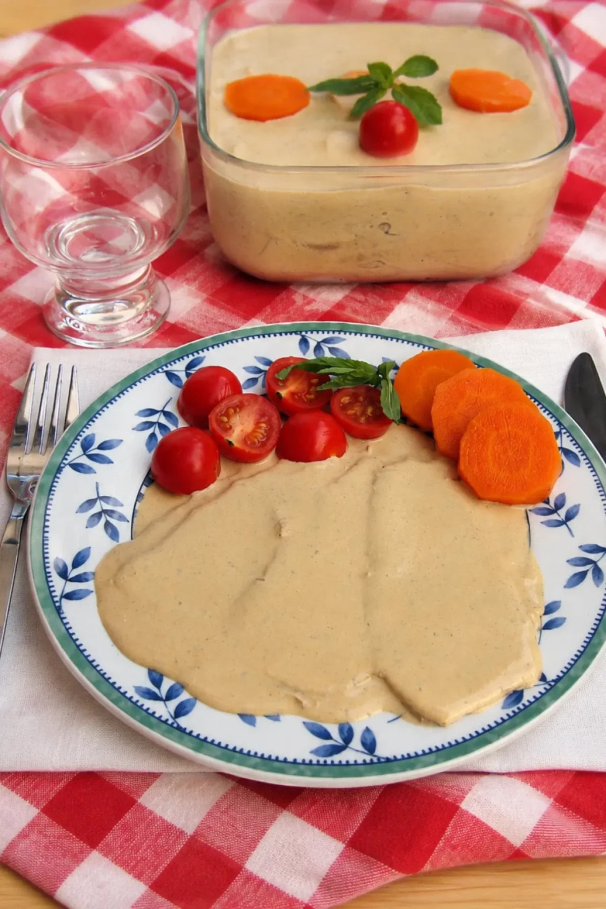 A plate with creamy beige sauce, sliced carrots, cherry tomatoes, and herbs on a blue and white dish—perfect for those seeking flavorful Italian dinner recipes.