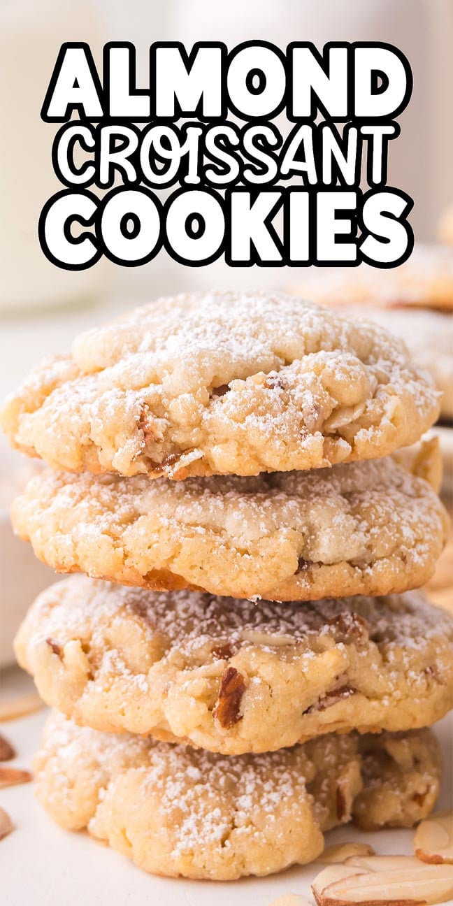 A stack of Almond Croissant Cookies dusted with powdered sugar, with almond slices scattered around.