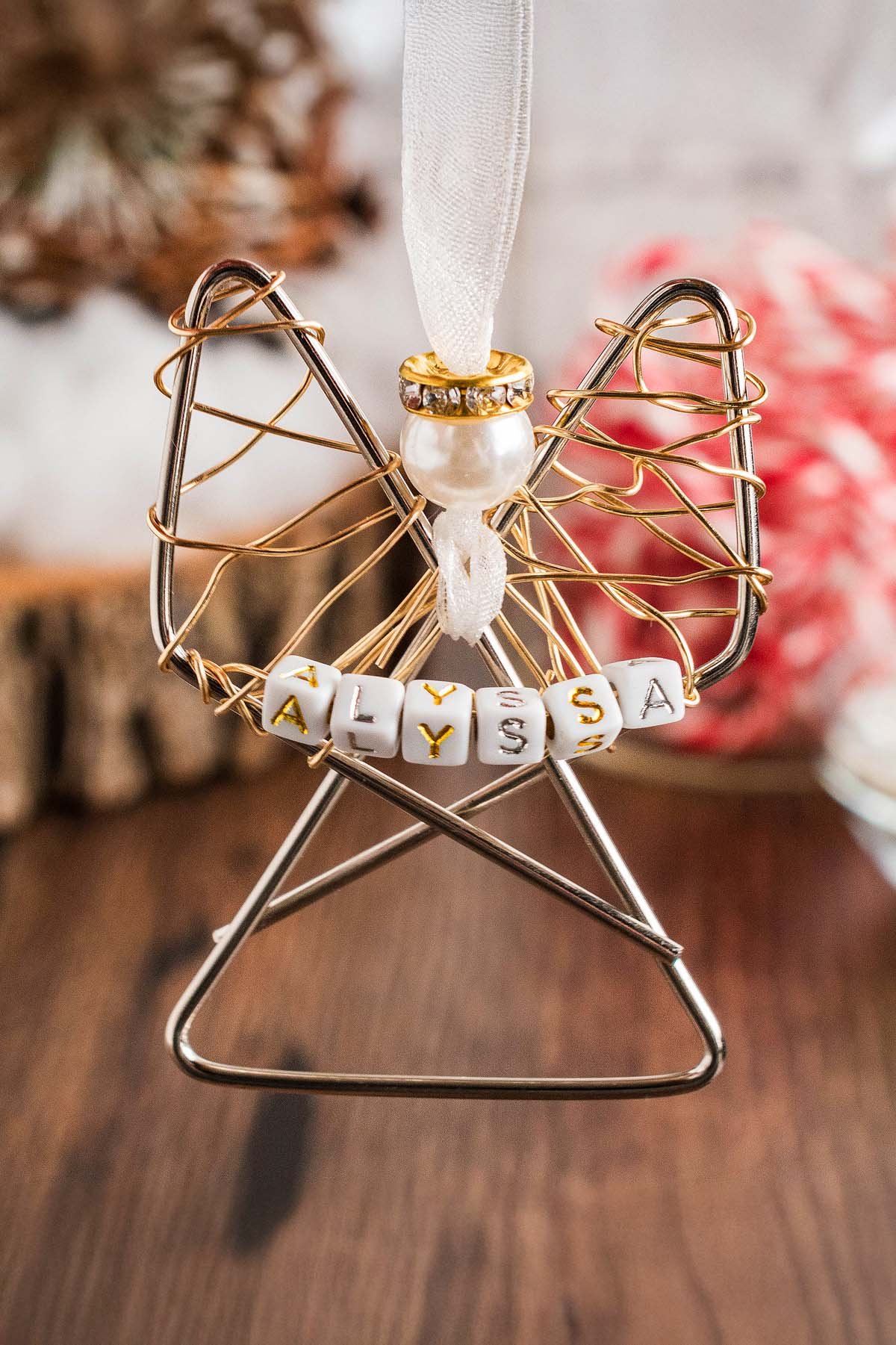 Easy personalized paper clip angel ornament with a pearl head and beads spelling "ALYSSA," hanging from a white ribbon.