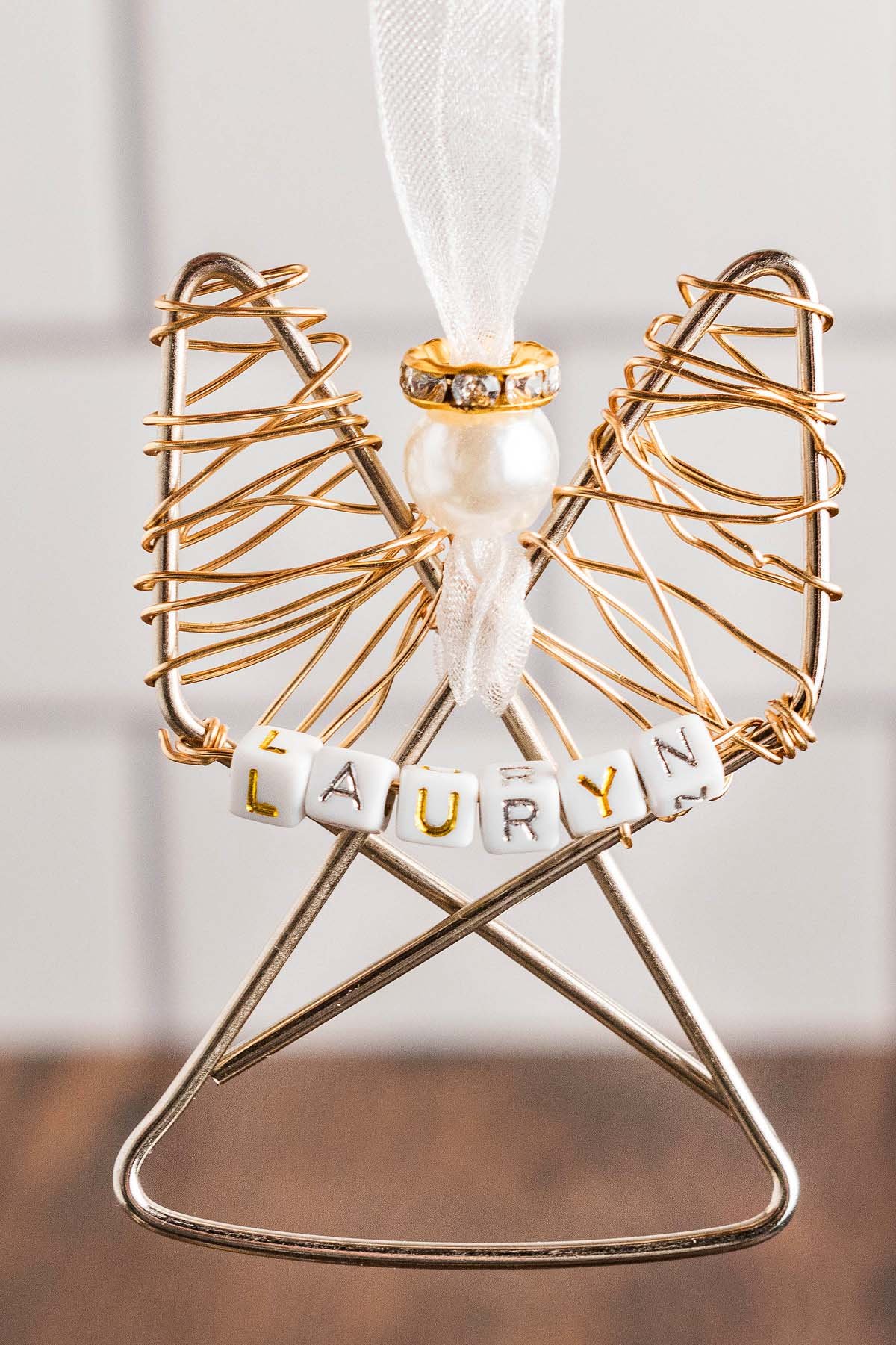 Easy personalized paper clip angel ornament with a pearl head, white ribbon, and beads spelling "LAURYN"—a charming keepsake for any occasion.