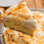 A slice of creamy Banana Pudding Pie with whipped topping and cookie pieces is lifted from the whole pie.