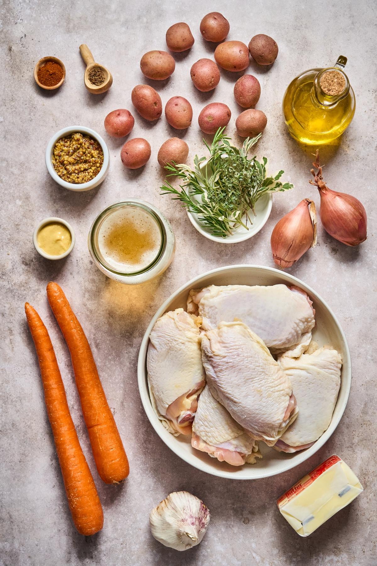 Raw chicken thighs, carrots, potatoes, garlic, shallots, herbs, spices, mustard, broth, olive oil, and butter.