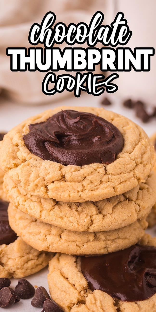 A stack of Chocolate Thumbprint Cookies filled with rich chocolate and surrounded by scattered chocolate chips.