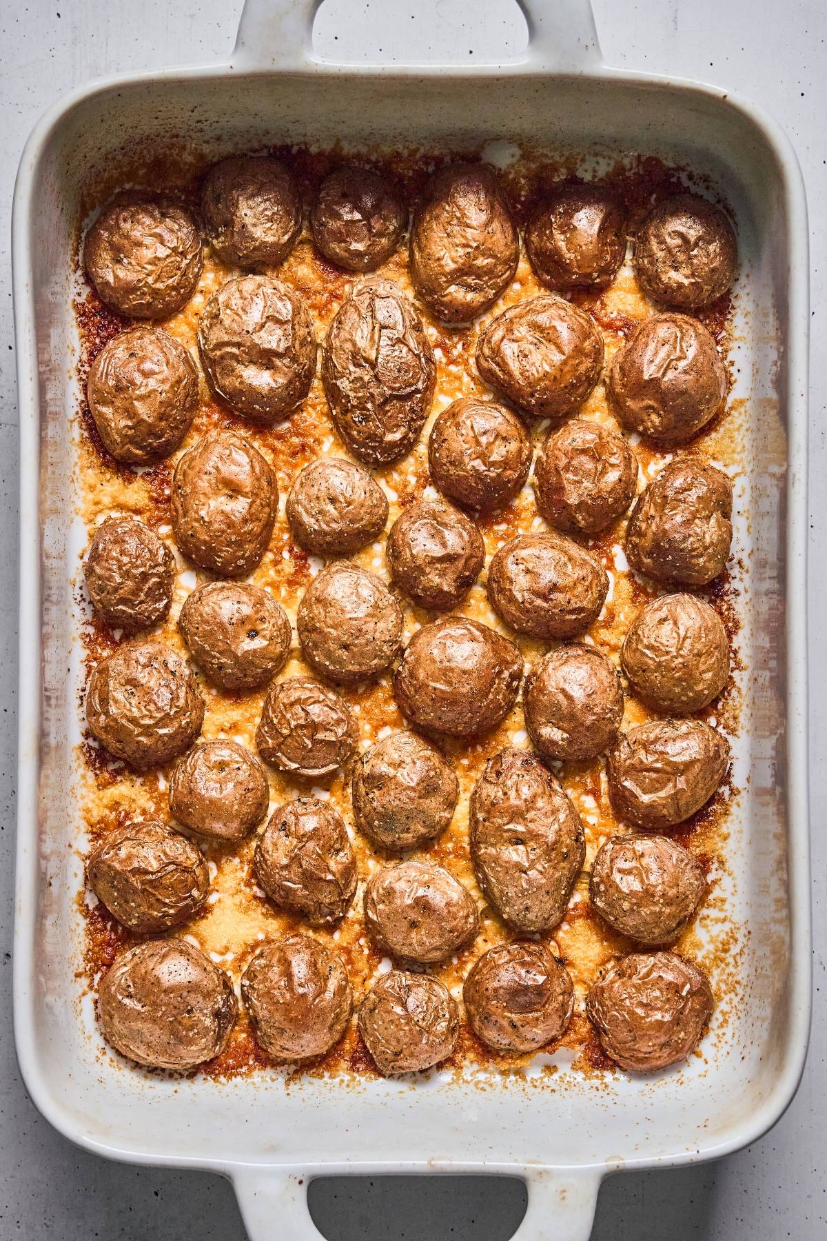 A baking dish filled with evenly roasted small potatoes with crispy, golden-brown skins.