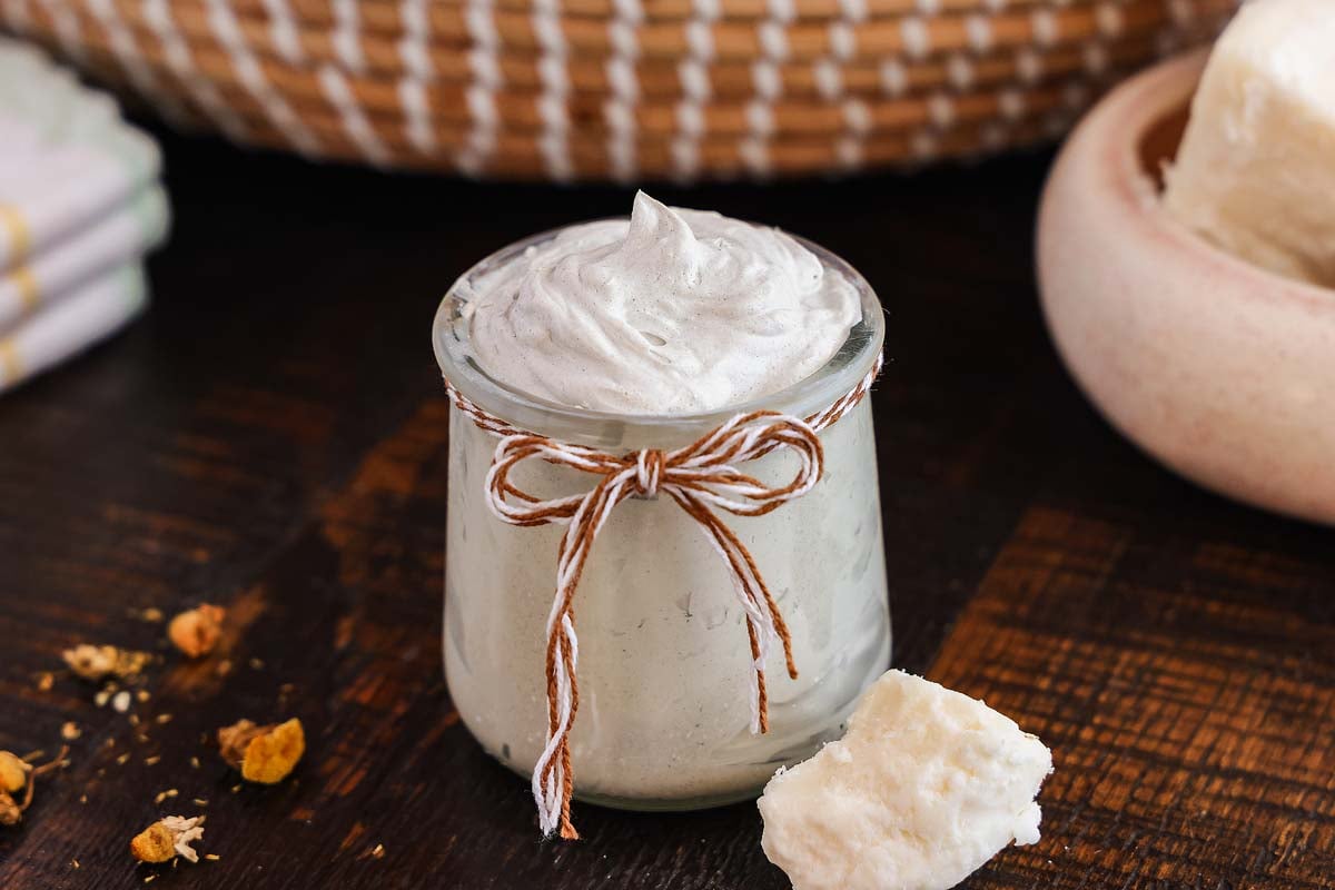 A small jar of homemade diaper rash cream on a wooden surface.