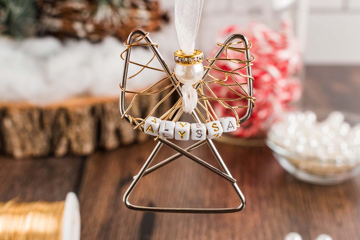 Easy personalized paper clip angel ornament with a pearl head and "Alyssa" spelled in beads, hanging by a white ribbon.