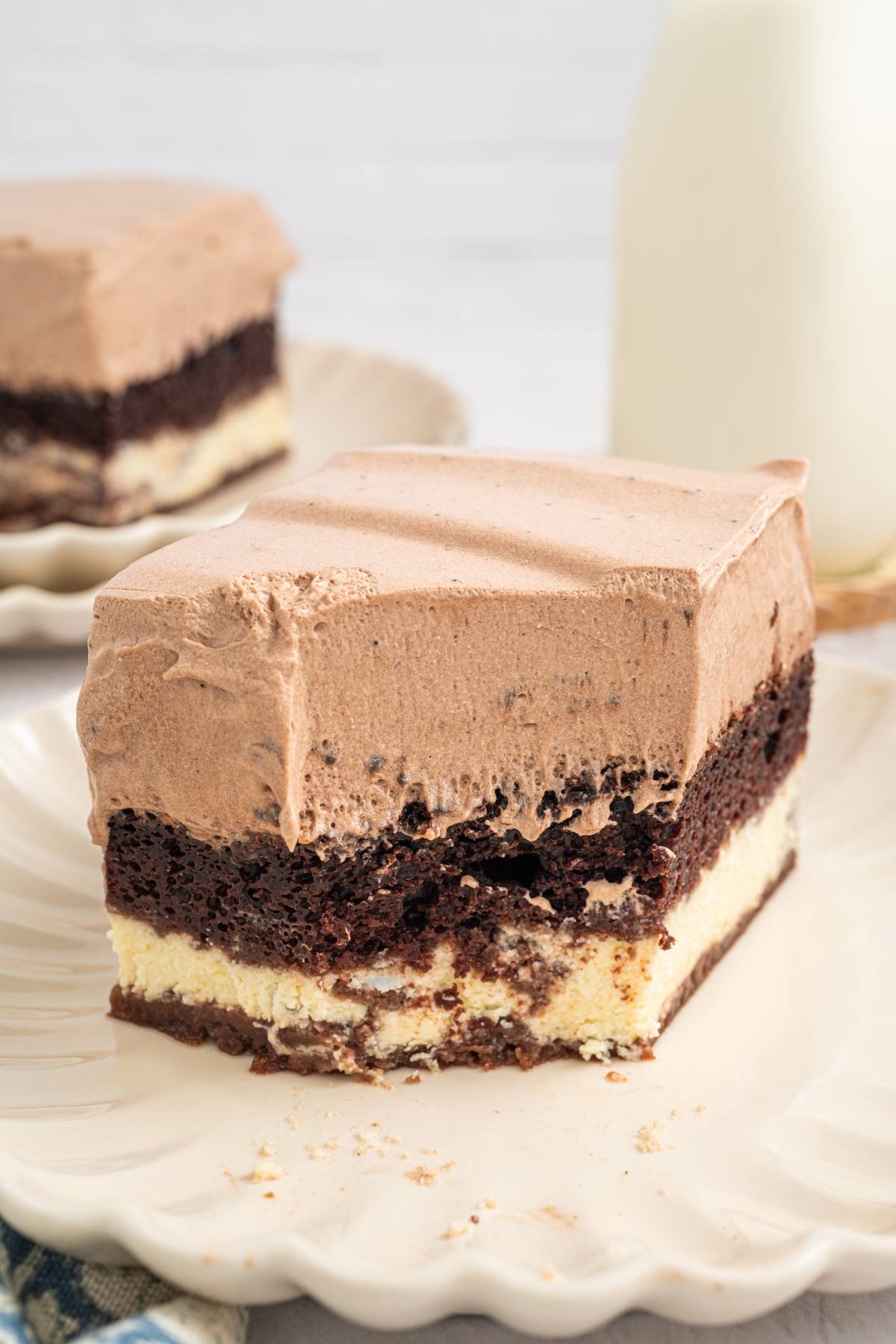 A slice of layered chocolate and cream dessert on a plate, with a bite taken out of the corner.
