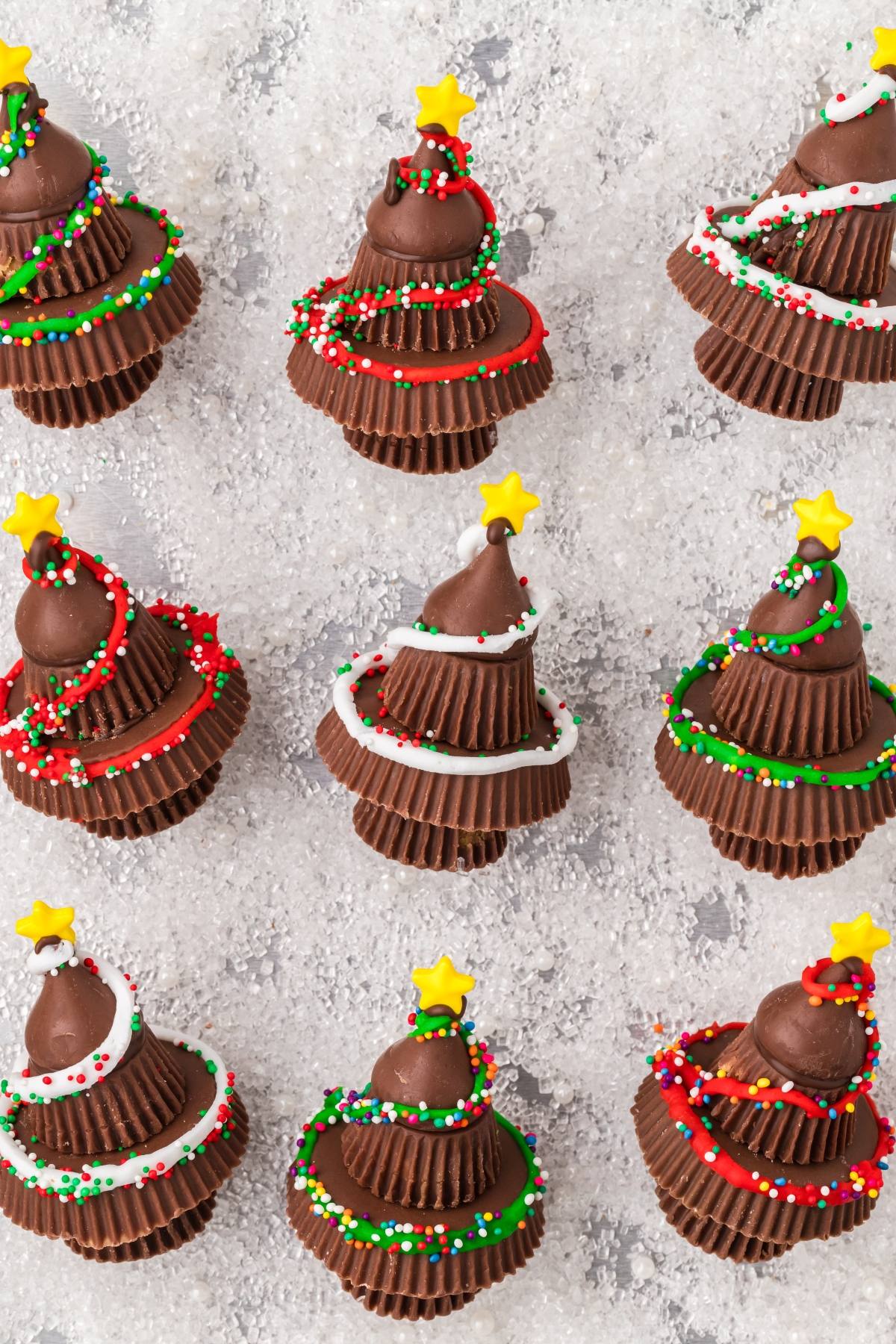 Chocolate candies stacked to look like Christmas trees, decorated with icing, sprinkles, and yellow star toppers.