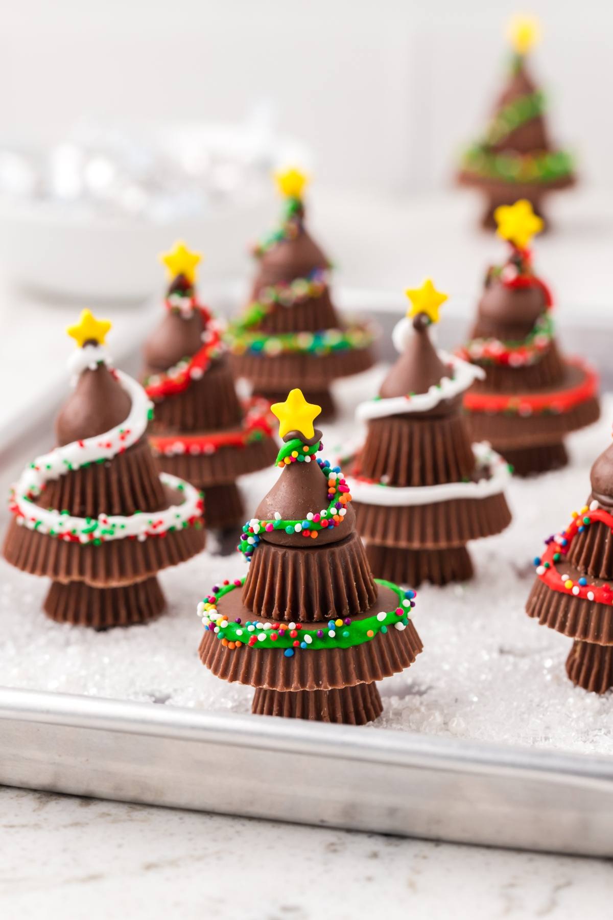 Chocolate Christmas tree treats made from stacked candies, decorated with icing, sprinkles, and a yellow star on top.