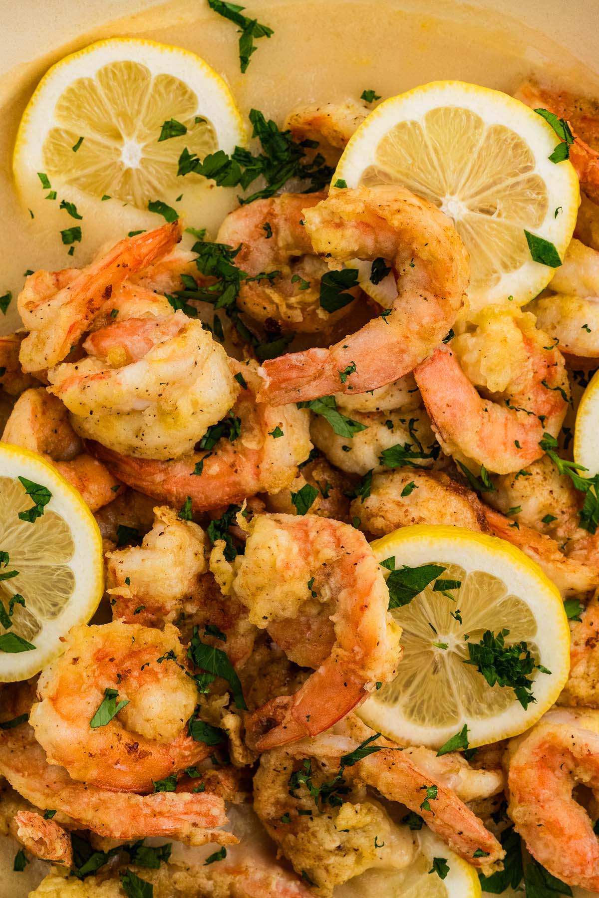 Cooked Shrimp Francese garnished with fresh parsley and lemon slices on a white plate.