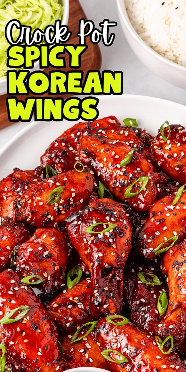 A plate of slow cooker spicy Korean wings garnished with sesame seeds and green onions, served with rice and fresh lettuce nearby.