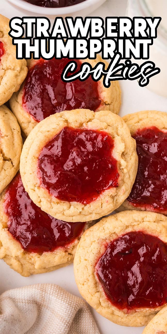 Strawberry Thumbprint Cookies topped with glossy red jam are beautifully arranged on a plate, making them a delightful treat for any occasion.
