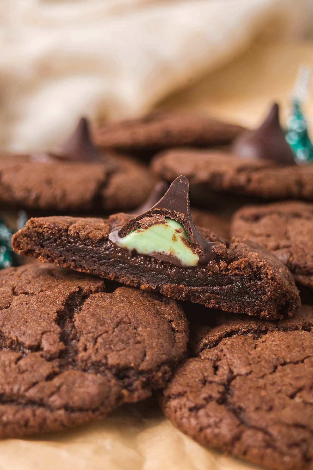 Chocolate Mint Kiss Cookies stacked on parchment paper, featuring a Hershey’s Kiss and cool mint filling for a delicious twist.