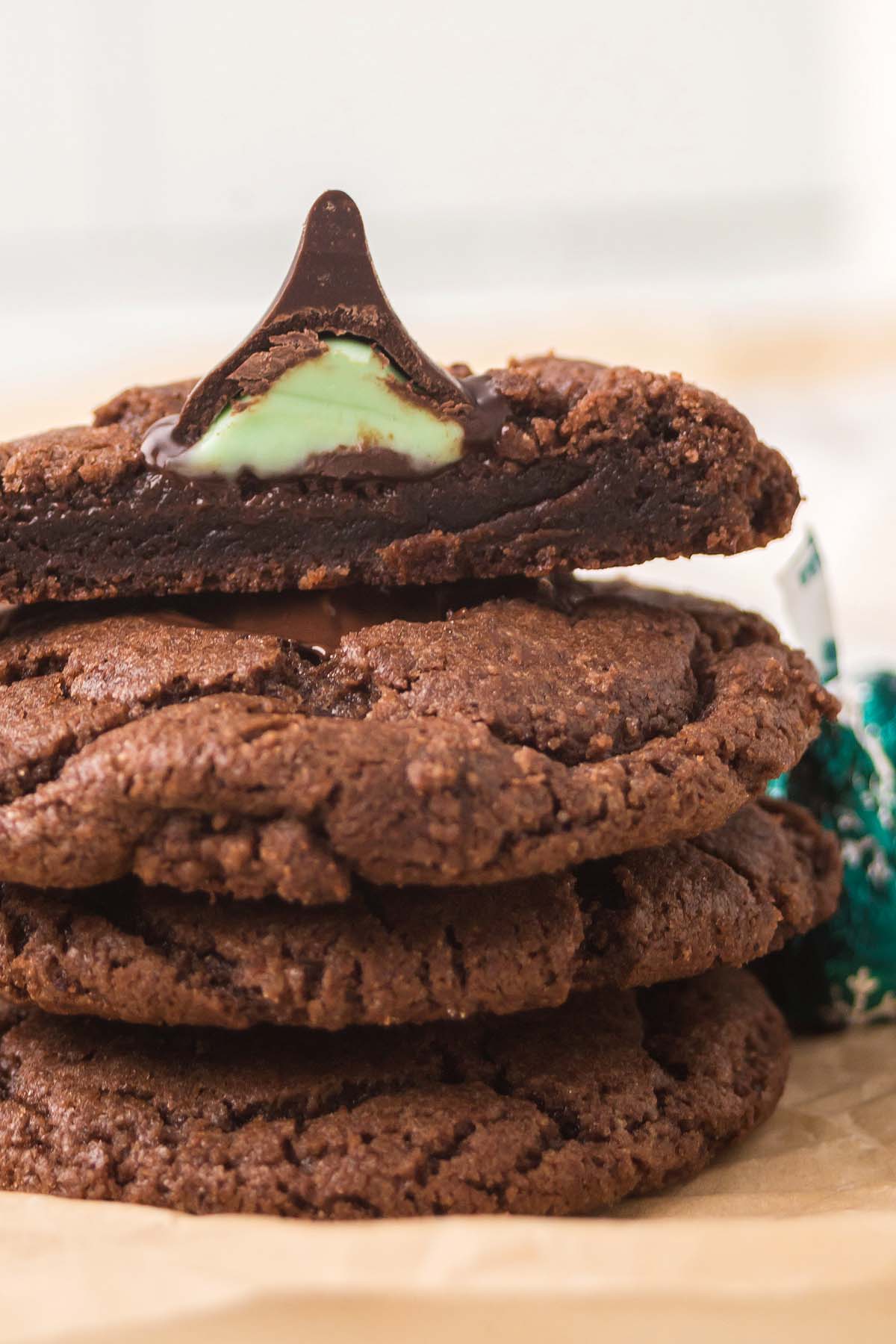 A stack of Chocolate Mint Kiss Cookies, one split open to reveal its irresistible mint chocolate candy center.