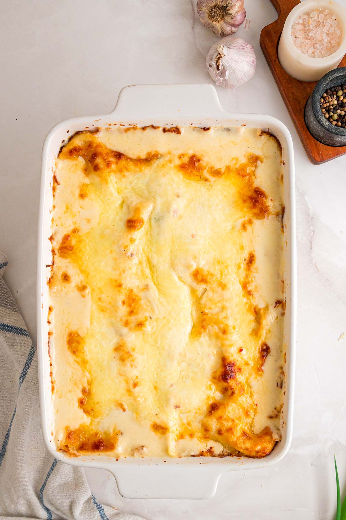 Baked seafood lasagna in a white rectangular dish, featuring browned edges and melted cheese bubbling on top.