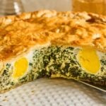 A savory Torta Pasqualina with a golden pastry crust, filled with spinach, ricotta, and whole hard-boiled eggs inside.