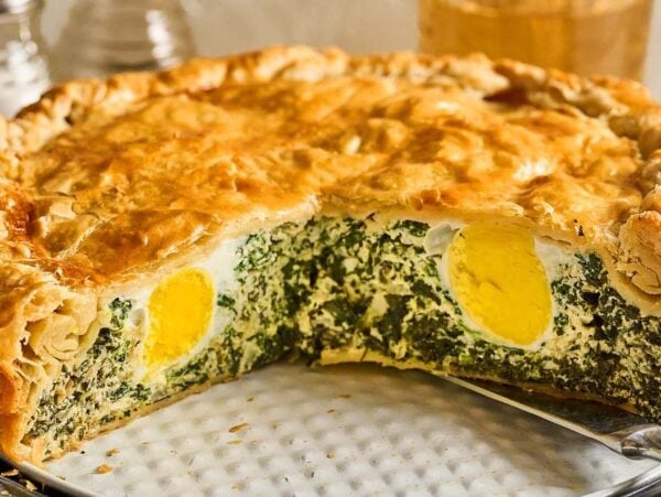 A savory Torta Pasqualina with a golden pastry crust, filled with spinach, ricotta, and whole hard-boiled eggs inside.