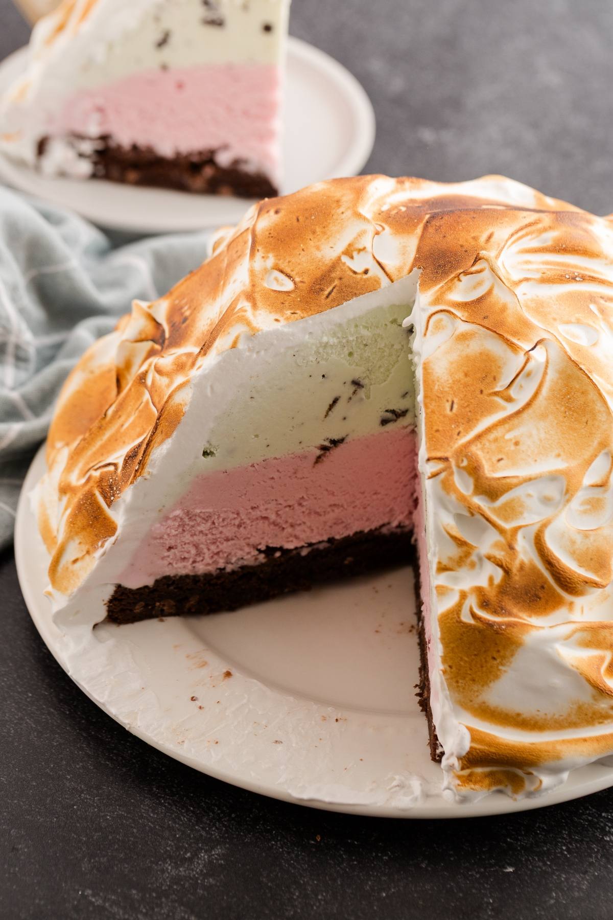 A sliced baked Alaska dessert with layers of ice cream and cake, topped with toasted meringue.