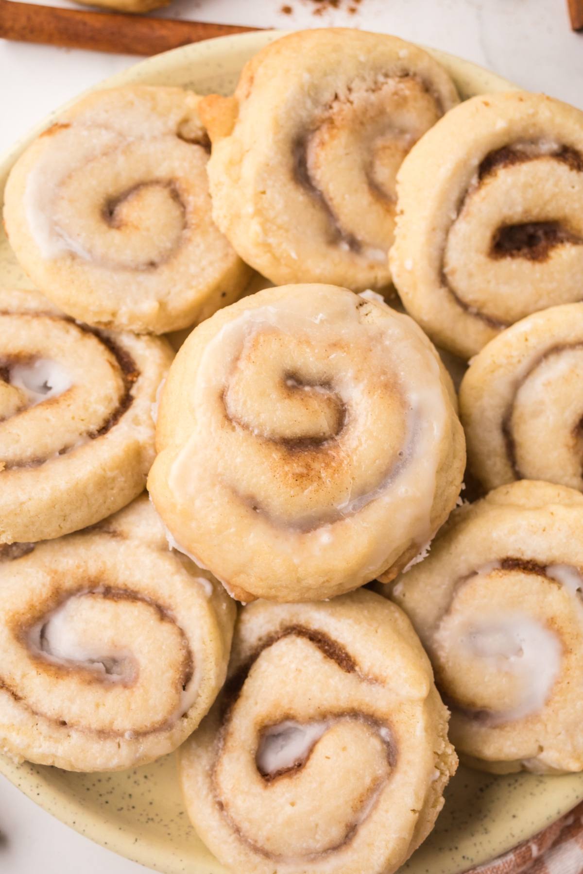 A plate of glazed cinnamon rolls arranged closely together on a light-colored plate.