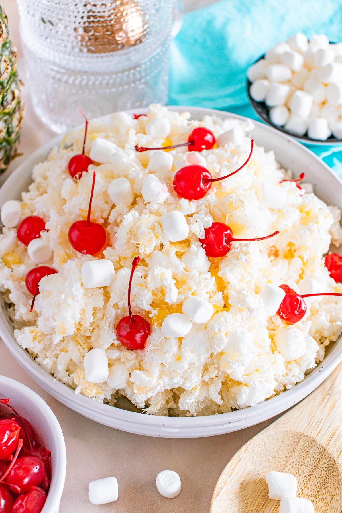 A bowl of glorified rice ambrosia salad topped with maraschino cherries and mini marshmallows.